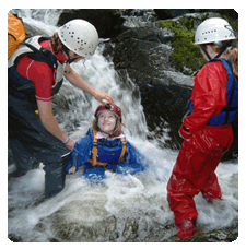 image of a child sitting under a waterfall with helmet on and big smile on her face