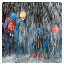 image of a group of four children underneath a waterfall with smiles on their faces