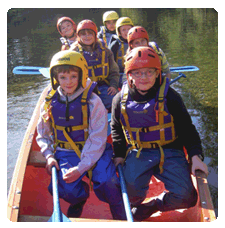 image of a group of 4 pairs of children smiling, each pair sat in rows behind each other facing the camera whilst sat in the voyageur open canoe