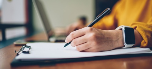 A photograph of a person completing a form on a clipboard
