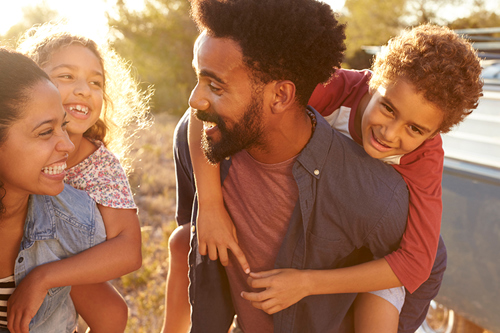 Picture of parents giving their kids piggybacks in an open space