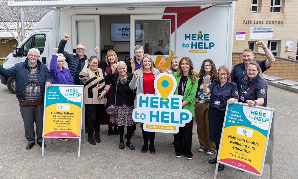 A photograph showing a group of people gathered outside the Here to Help bus in Telford.