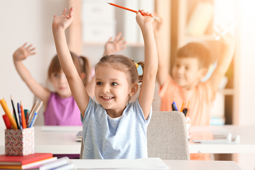 Picture of children putting their hands up in an education setting.