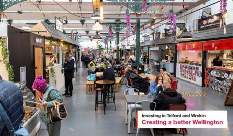 A picture of people inside Wellington market, shopping, eating and drinking.