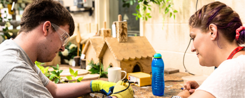 Two people in a workshop working on a wood project
