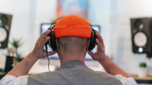 A picture of a person with an orange beanie with headphones
