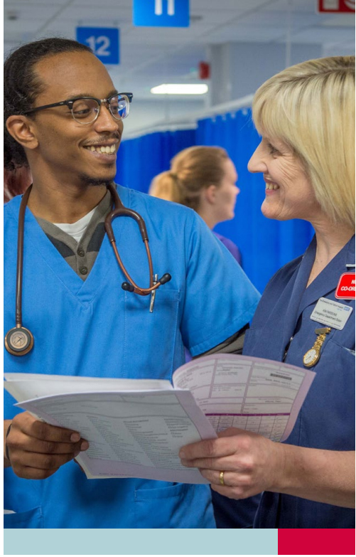 Two hospital staff members discussing medical documents in a busy hospital setting.