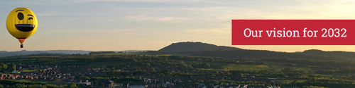 A photo of the wrekin from the air with a hot air balloon in the sky