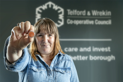 Image of Kelly holding an orange button