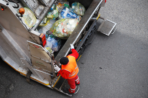 Picture of a man loading household waste into a waste truck.