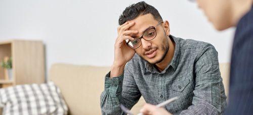 A teenage boy holding his head in his hand listening to an adult explain their options