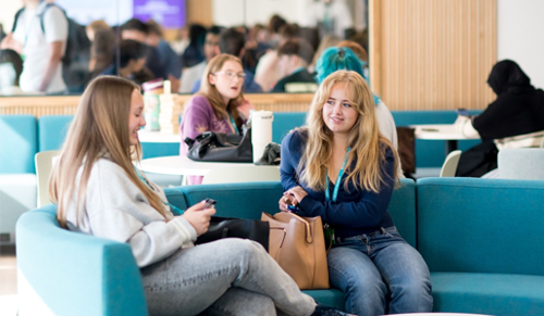 Students sitting and talking in a modern college or sixth-form study area with informal seating.