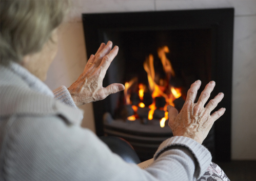 Image of an elderly lady sat in front of a fire