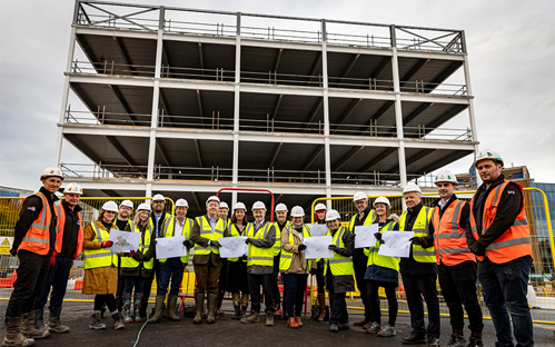A picture of a partially developed building with a group of builders standing in front of it..