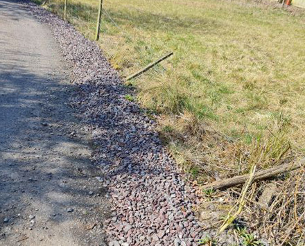 A photo of stones and chipping on the side of a path used for water runoff