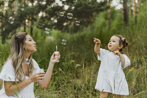 A mother blows soap bubbles for a child in the Park.