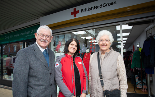 A picture of three people stood out side the British Red Cross shop at Wellington.