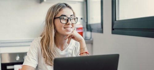 A teenage girl looking happy whilst using a laptop
