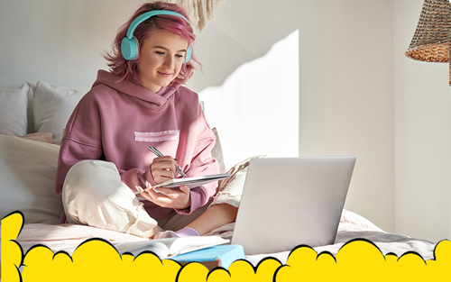 A picture of a teenage girl, school student with pink hair wearing headphone and writing notes from her laptop.