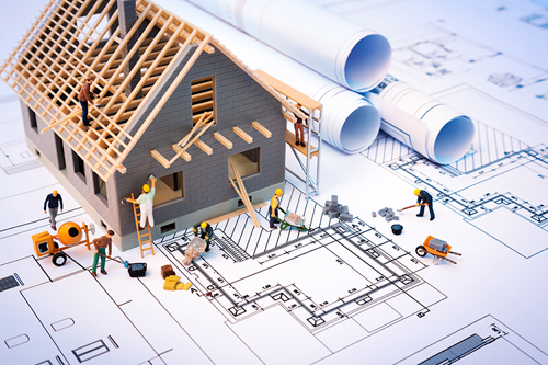Picture of a house being built, sat on top of the blueprints.