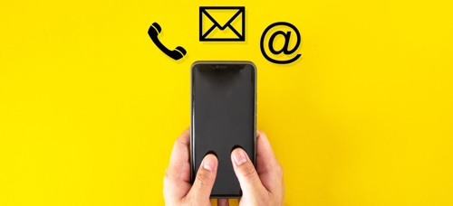 A mobile phone being held in a persons hands which icons for a phone call, text message and email displayed above the phone