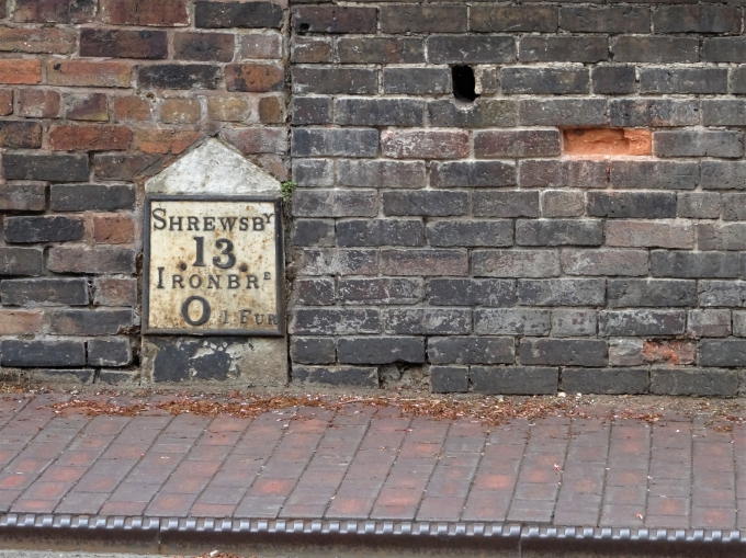 Historic milestone set into the wall of the Wharfage in Ironbridge and cast-iron kerb-edging